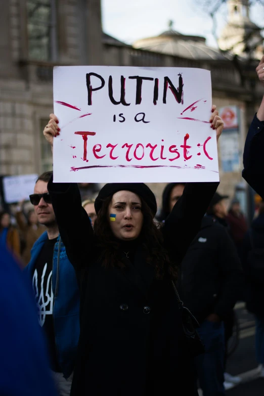 a woman holding a sign saying'putlin is a terrorist '