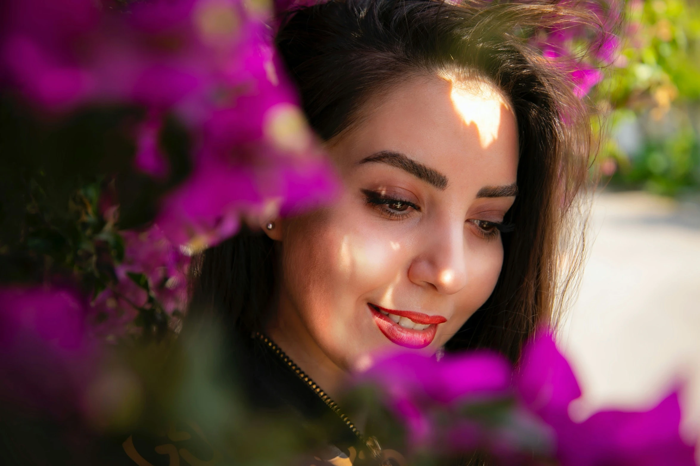 a woman with brown eyes looking over purple flowers