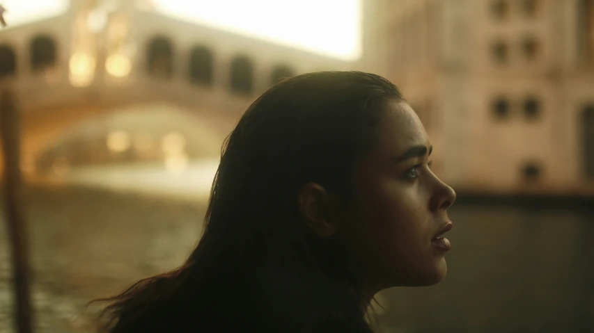 a woman looking into the distance in front of a bridge