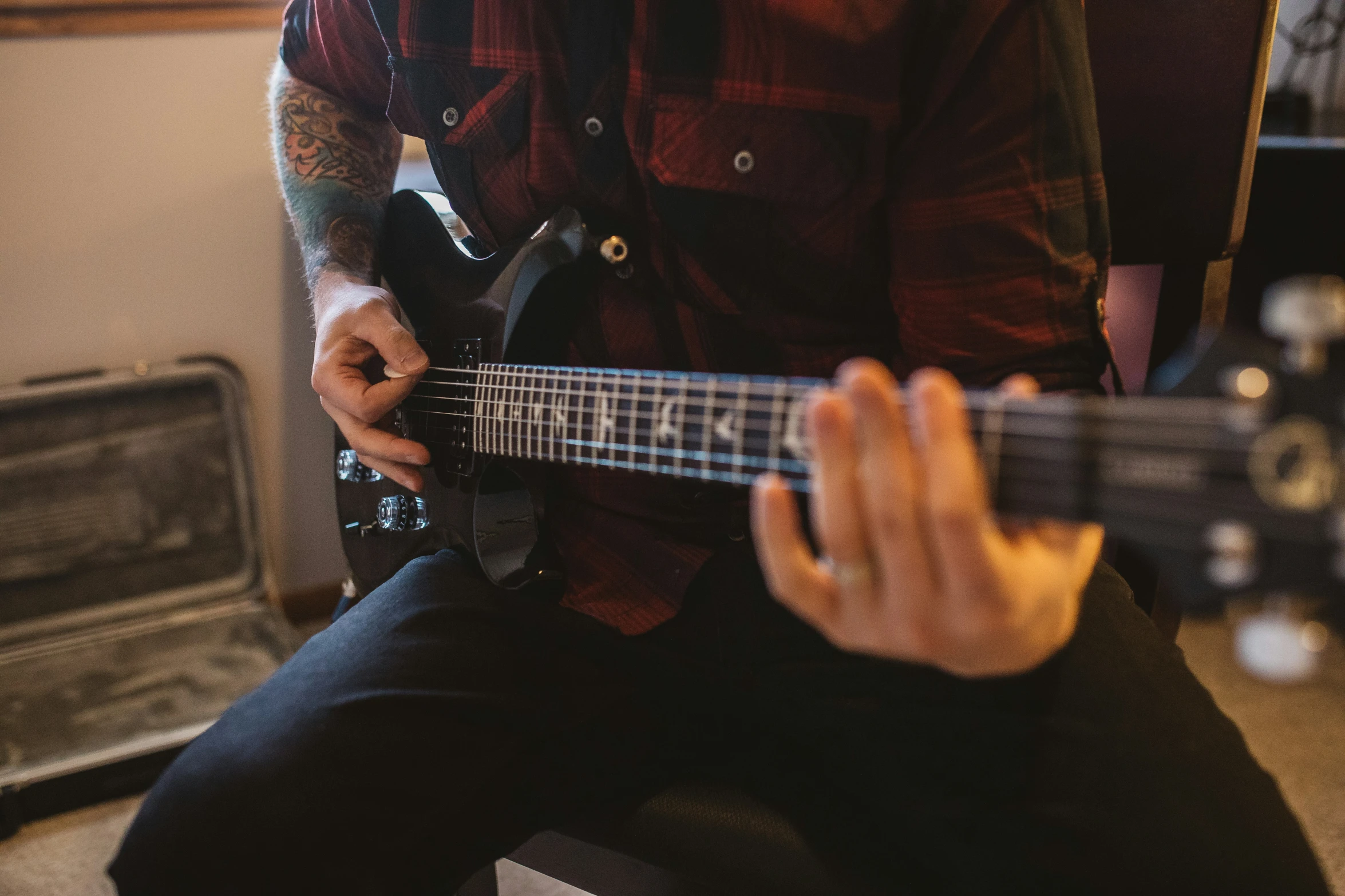 a man holding a guitar while wearing a red shirt