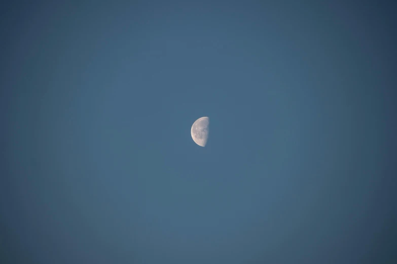 the moon is clearly visible in the clear blue sky