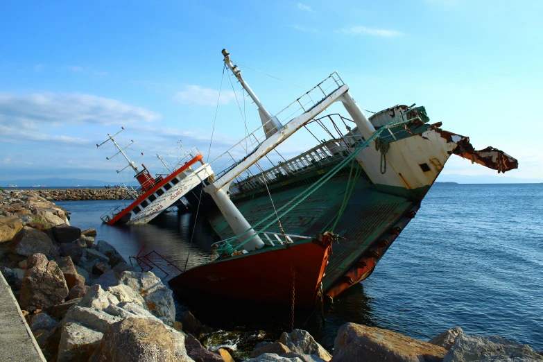 a large rusted boat sits in a bay next to some rocks