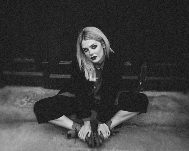 a blonde woman wearing all black is posing on the floor