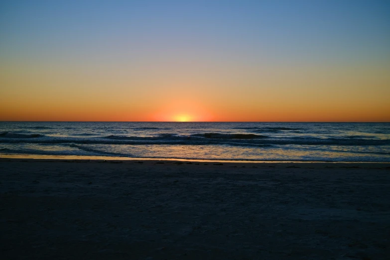 sunset over the ocean with waves coming ashore