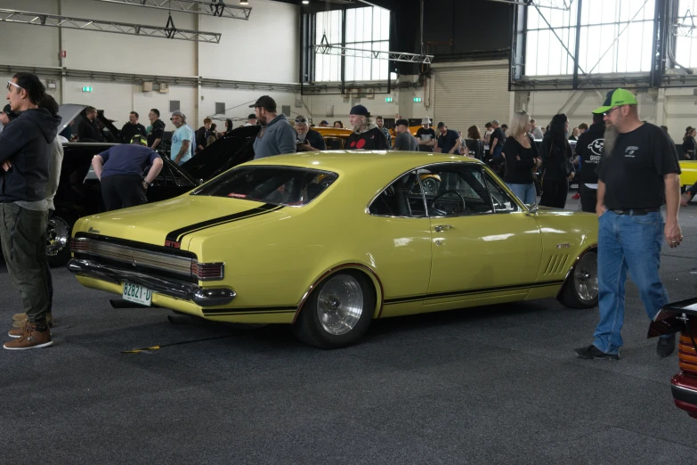 a yellow old fashioned car with the hood open