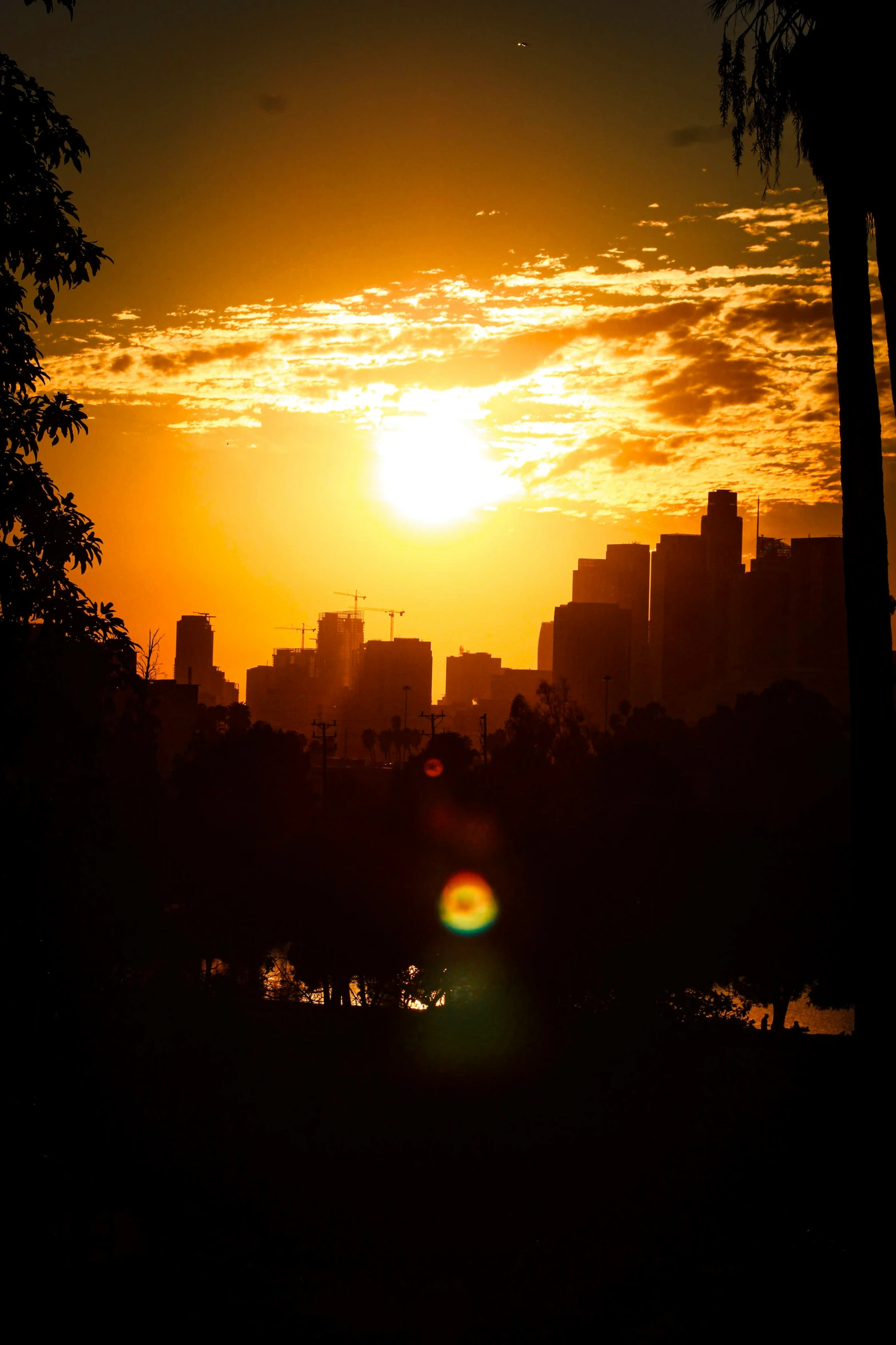 a sun sets over the city skyline from a distance