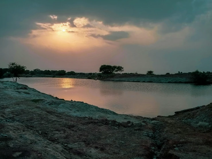 the sun sets over the edge of a body of water