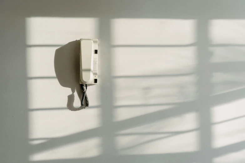 a phone hanging on the wall with a shadow of light on it