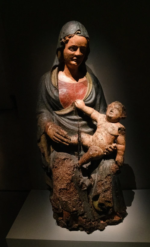 a statue of a woman holding a baby and a pig