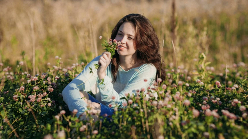 a girl is sitting in the tall grass