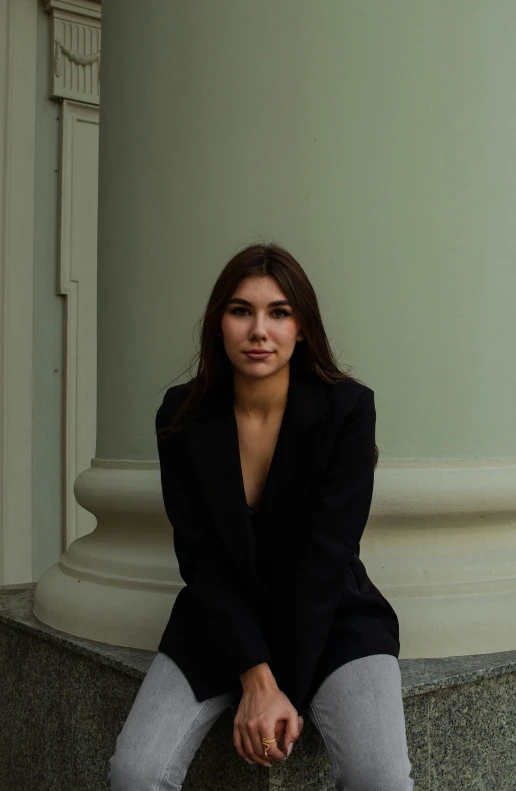 a woman is sitting on the side of a pillar