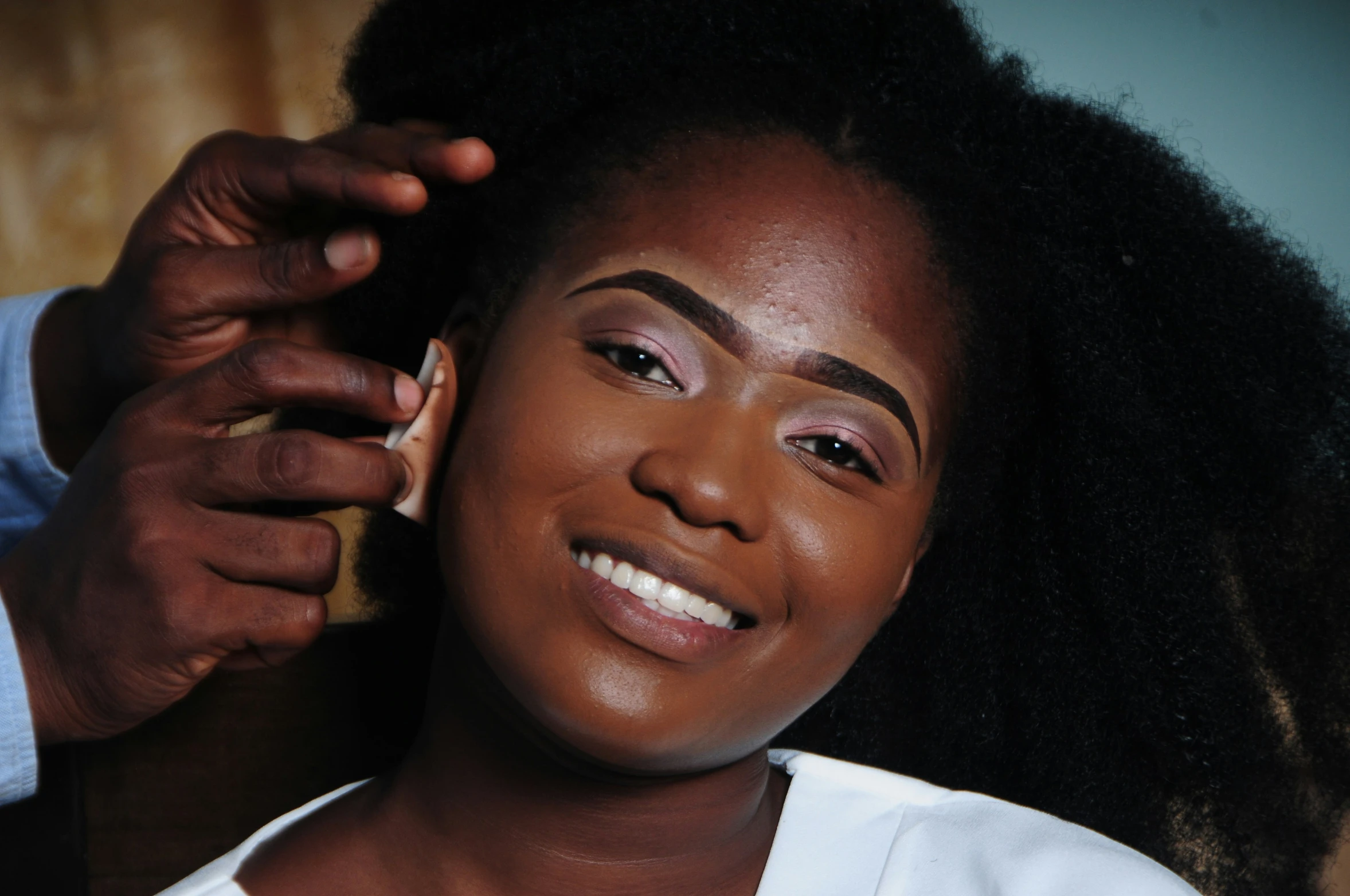 a lady is smiling while her make up artist combs her hair