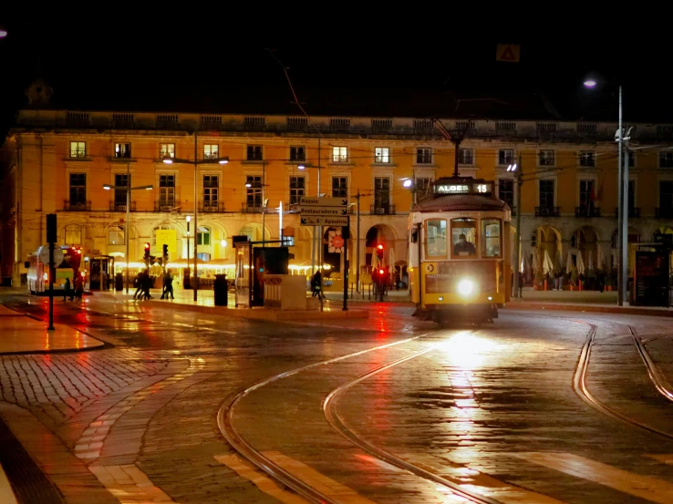 an old fashioned trolley travels down a deserted intersection at night