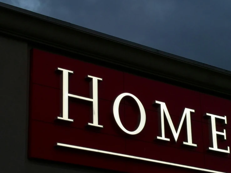 a lit up home sign next to a large red building