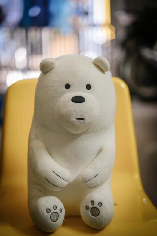 a stuffed polar bear sits on a yellow chair