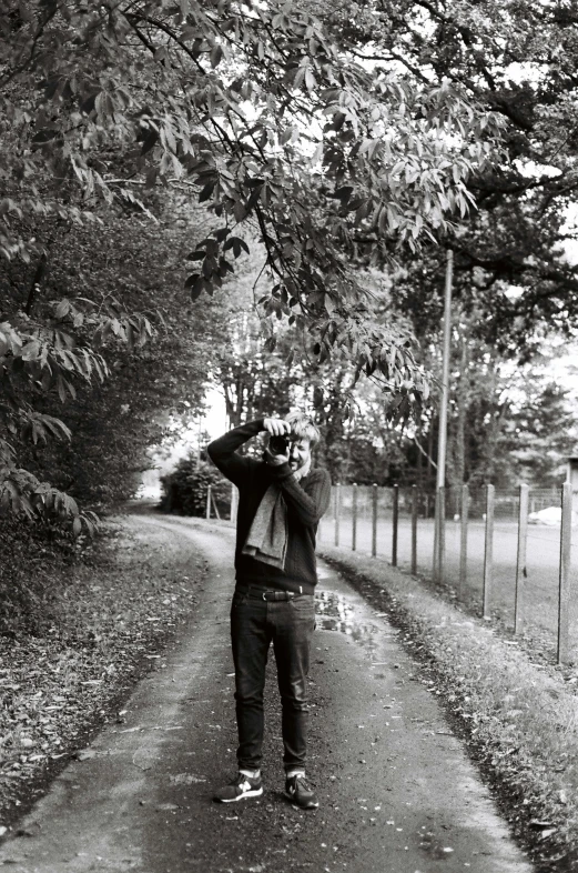 a man stands on a path holding his head to his forehead