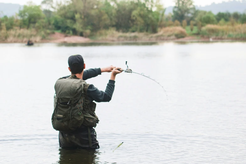 a man in a blue shirt fishing in the water