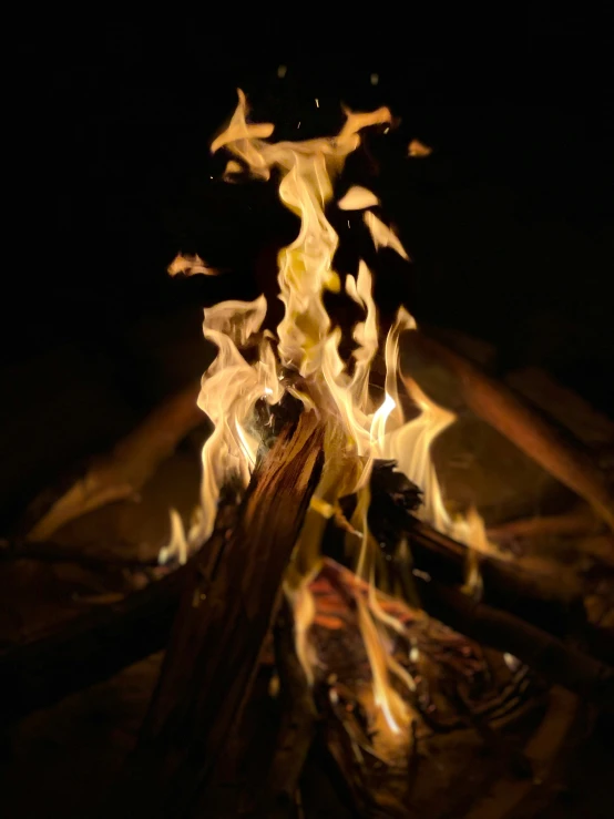 a campfire with large flames lite up in the dark