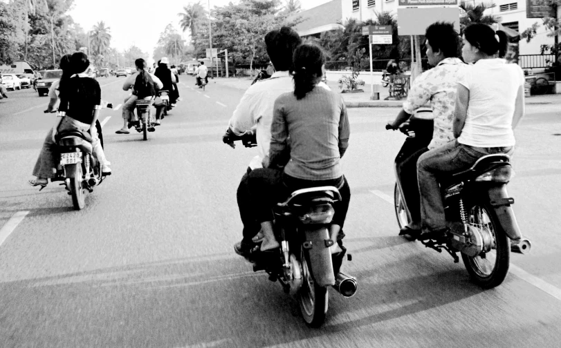 two men riding motorcycles in the street and some women on motorcycles