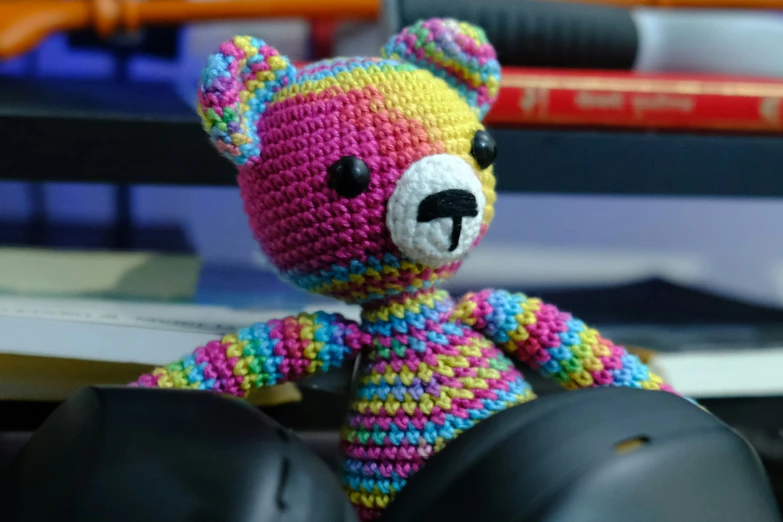 a colorful teddy bear sitting beside a pair of headphones