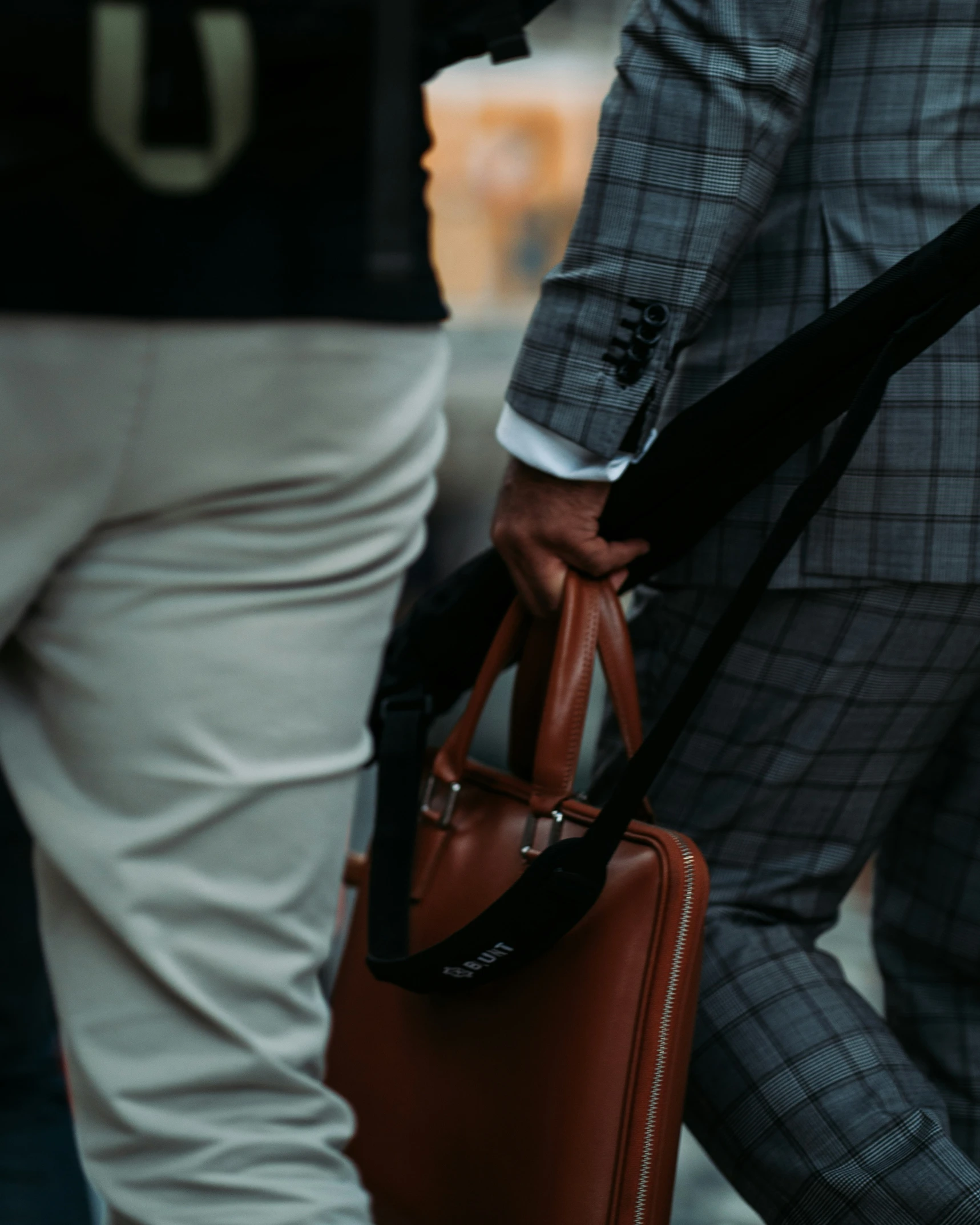 two people in suits carrying bags, one brown