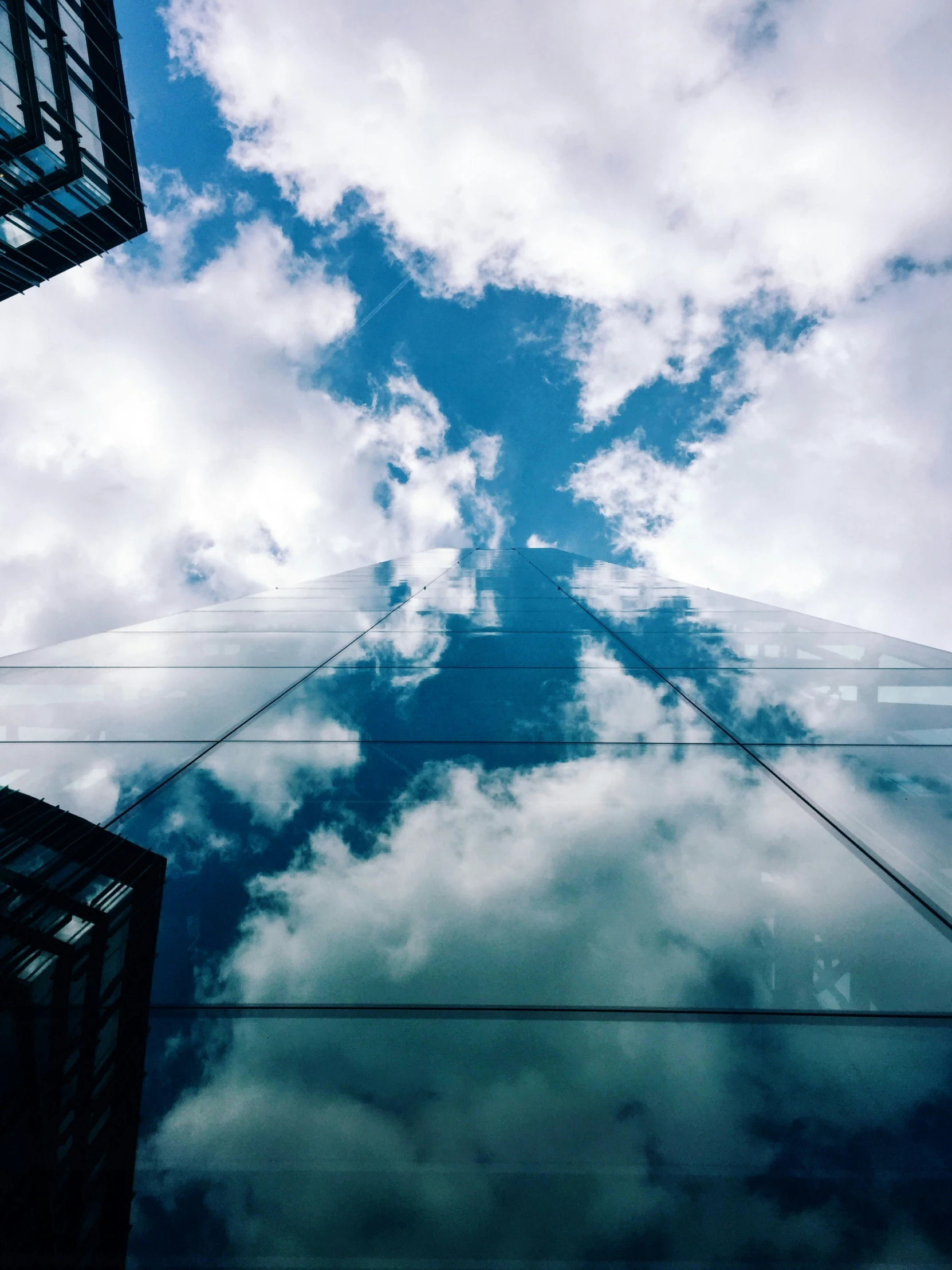 looking up at a building's reflection with a cloudy sky