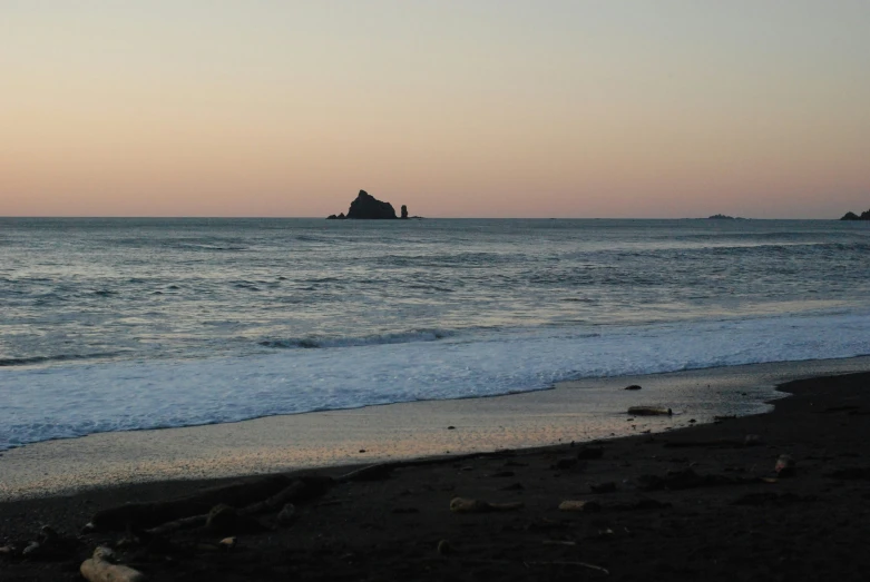 a beach with a big rock in the ocean