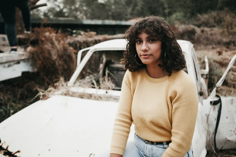 a woman is standing near a broken down car