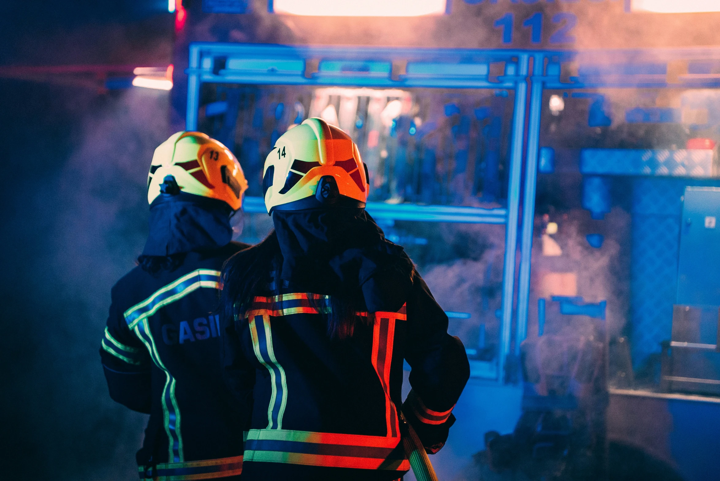 two fire fighters standing next to each other in front of a building