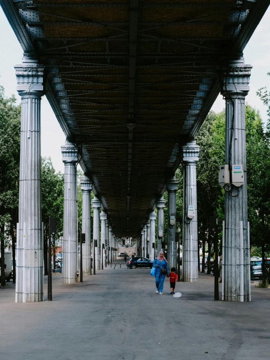 a woman is walking underneath a structure with trees