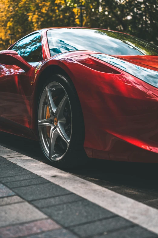 red ferrari parked next to a road in front of trees