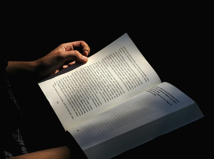an open book being held up in front of a person with their hand holding soing