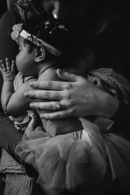 a mother holds her baby as it wears a large ring