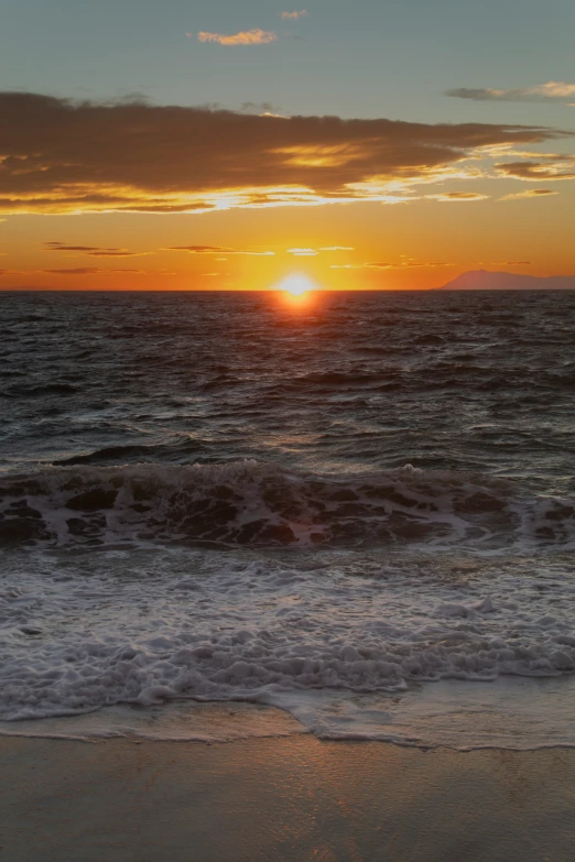 the sun is rising over an ocean and waves