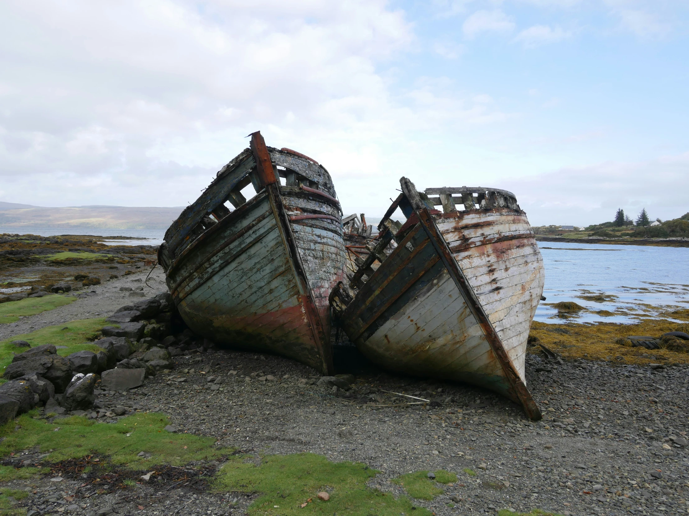 two large old, rusted boats sit side by side in the sand