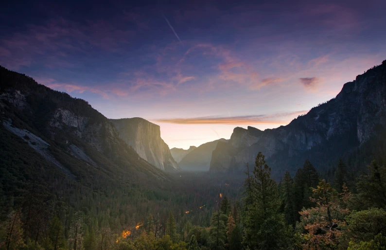 the sun shining over a mountain range with trees