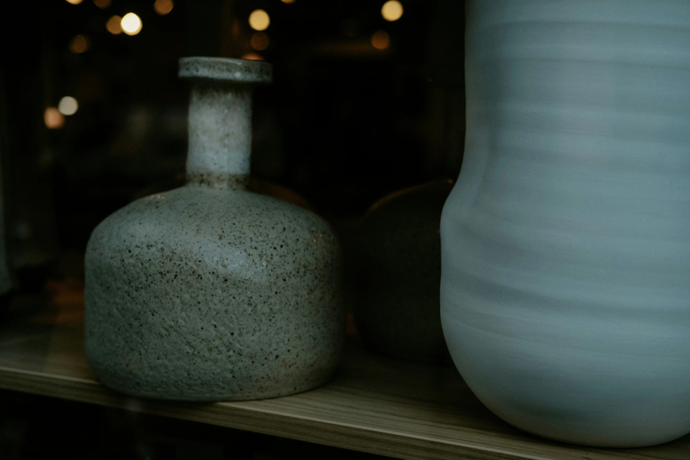 a white vase sits in front of a smaller white vase