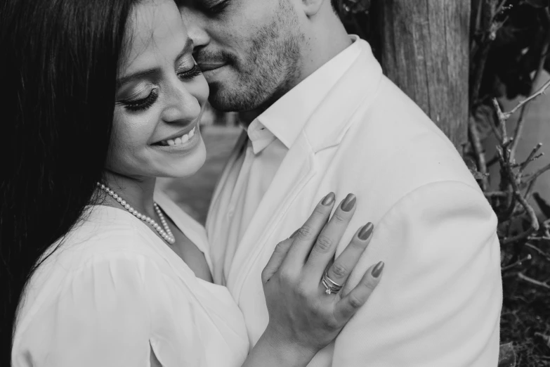 a man and woman hugging next to a tree