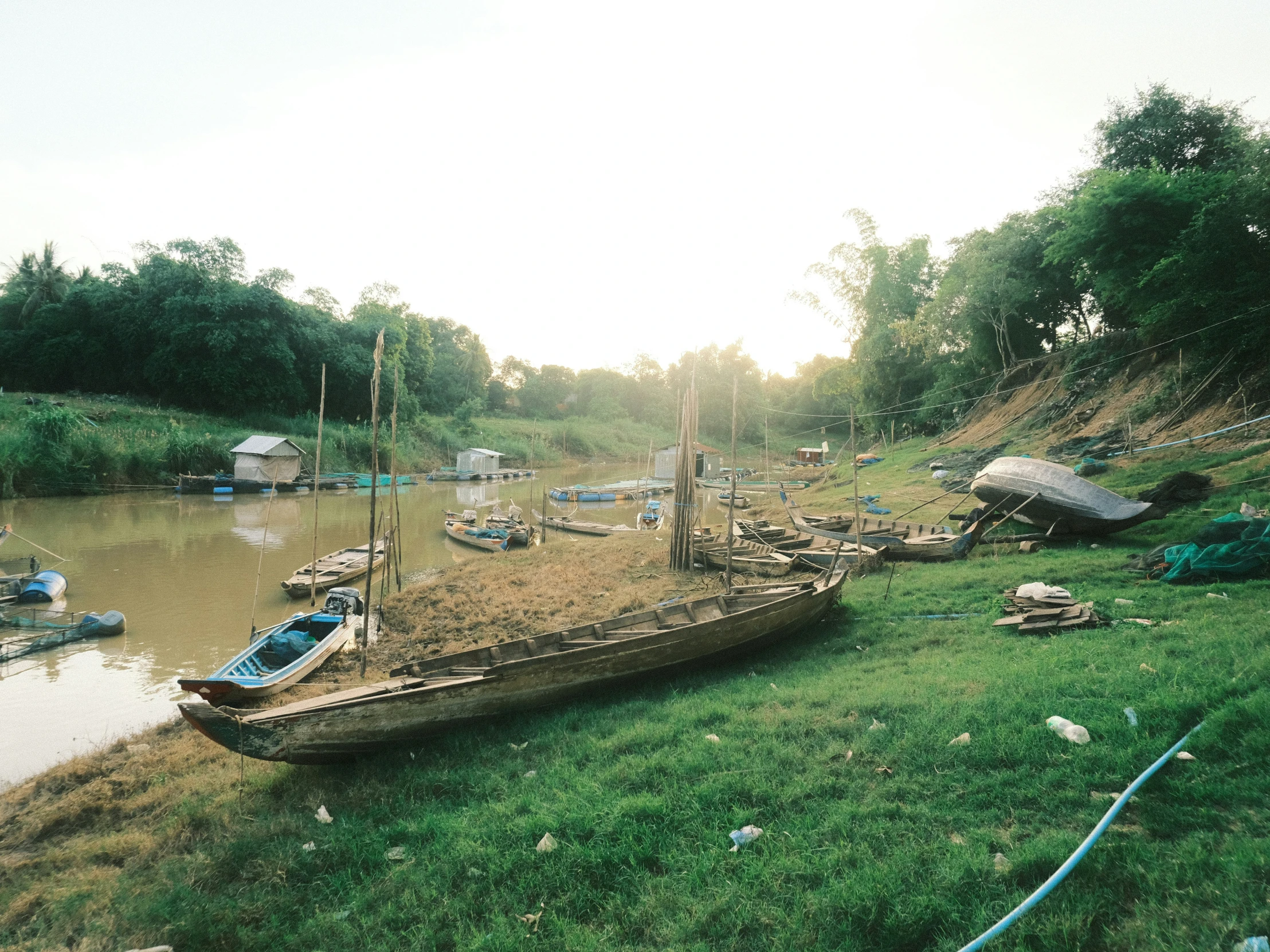 a boat sitting in a river next to a lush green field