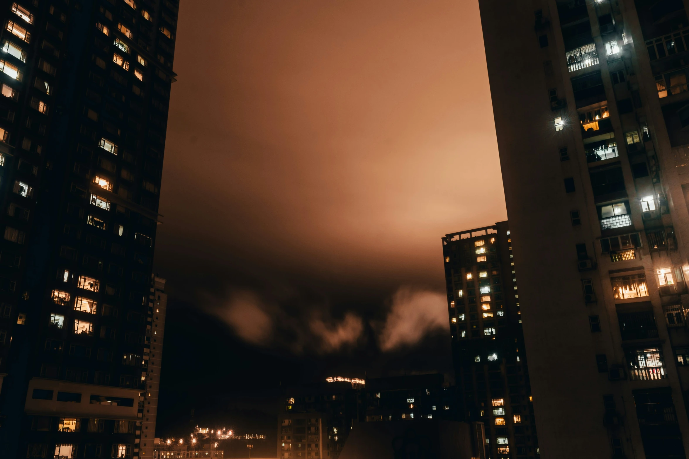 an evening view from a city street of tall buildings and a sky filled with clouds