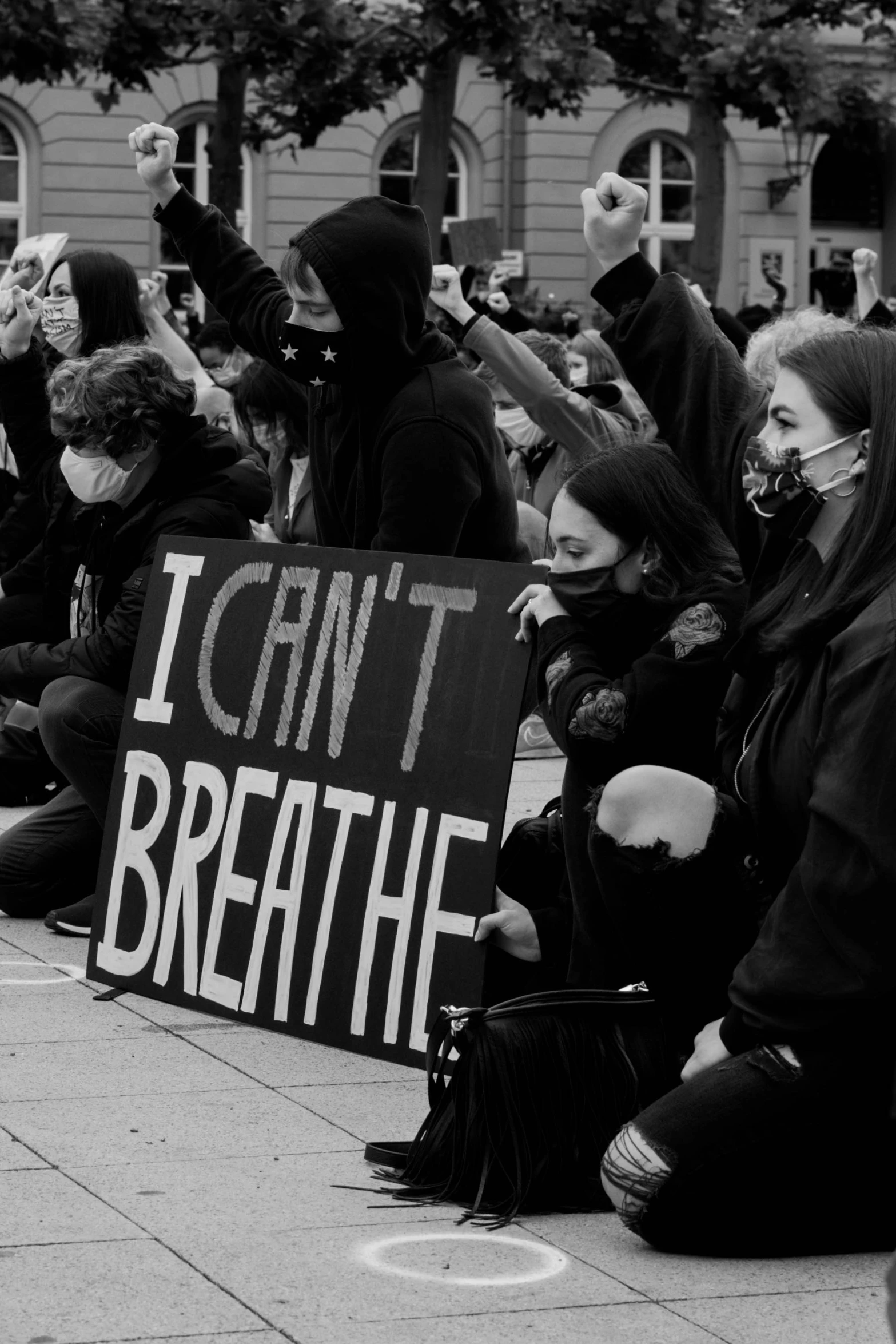 black and white image of people sitting on a sidewalk with signs