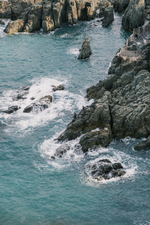 two people are standing on the rocks watching another one