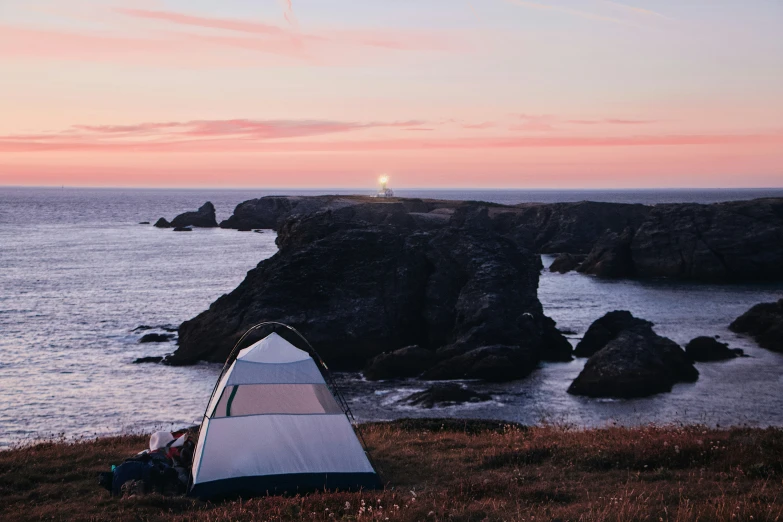 a tent pitched up on top of a lush green hillside