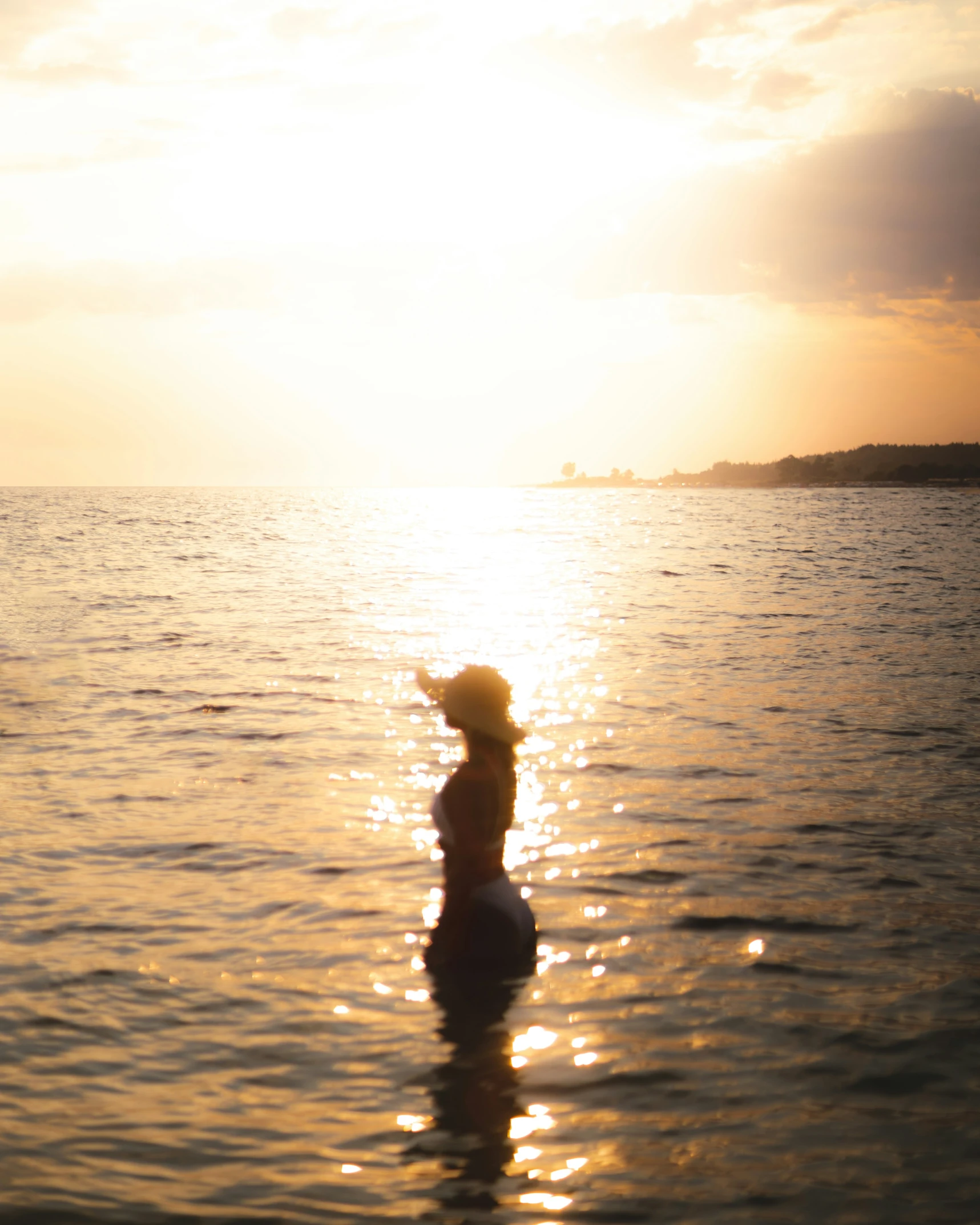 a person is wading in the water at sunset