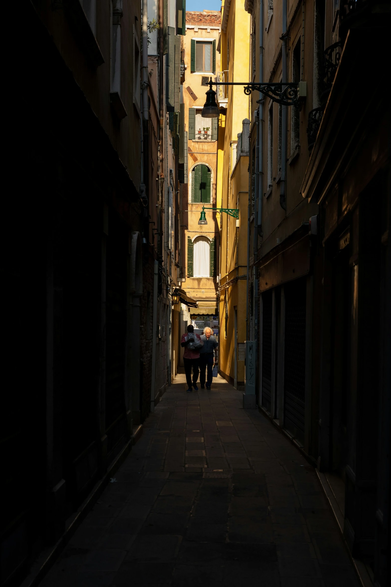 two people walk down the alley between buildings