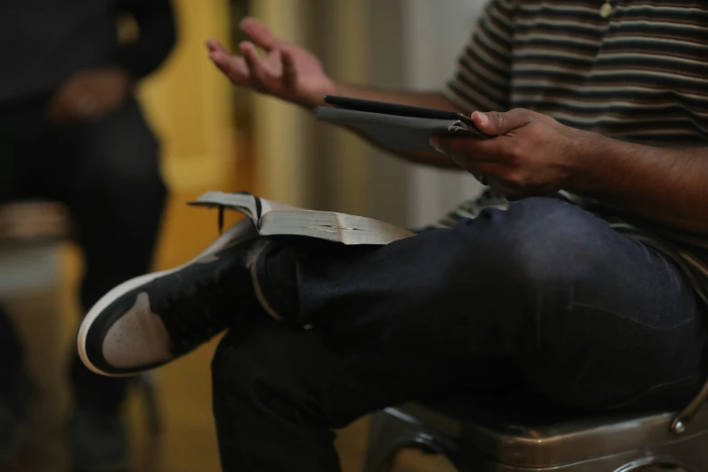 someone sitting on top of their chair and holding their cellphone