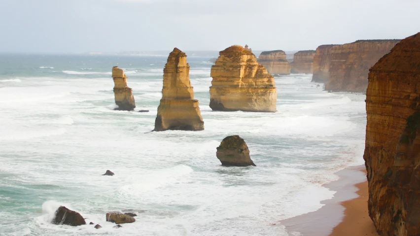 large rock formations stand out in the water at the beach