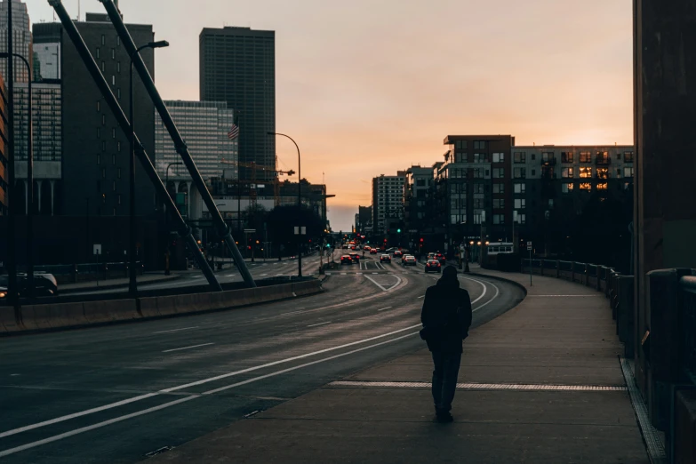 a person walks down a highway at sunset