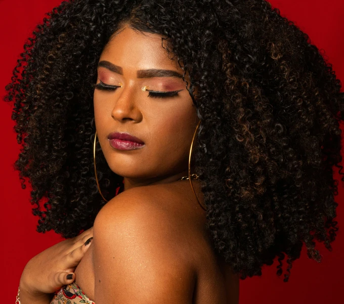 an african american woman with large earrings and a red background