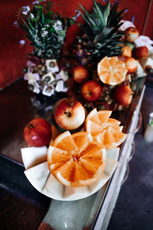 fresh fruits displayed on ceramic dish next to flower vase